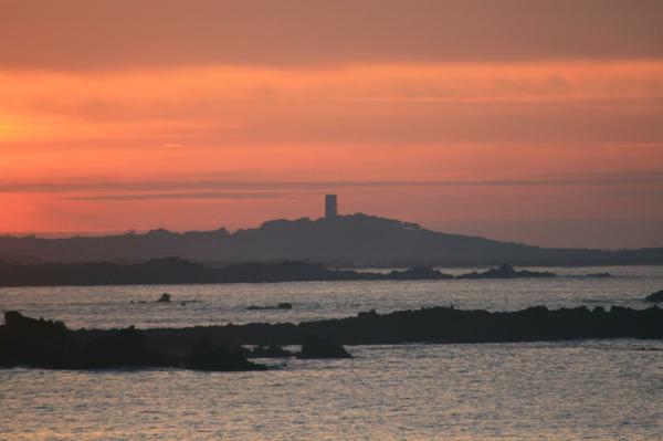 A German tower from the WWII is silhoutted against the sunset.
